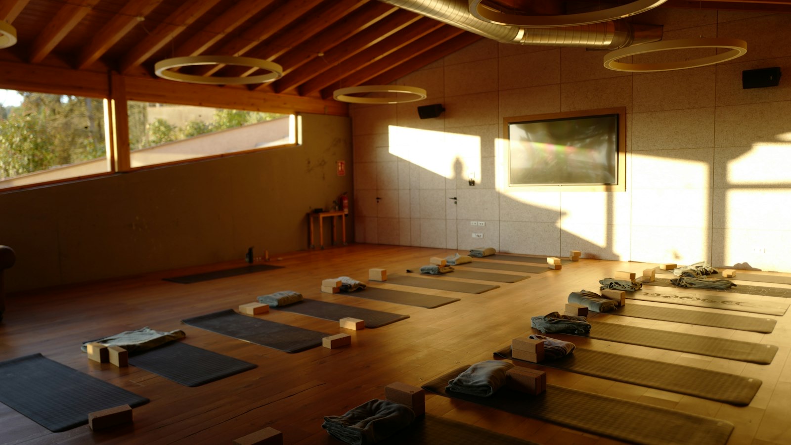 Yogazaal met houten vloer, klaargelegde matten en blokken in de avondzon
